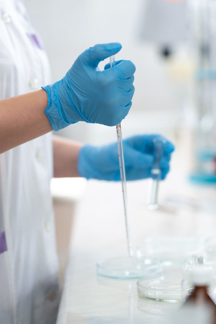 Close-up of a lab technician using a dropper in scientific research.